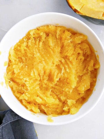 cooked acorn squash mashed with a fork in a bowl