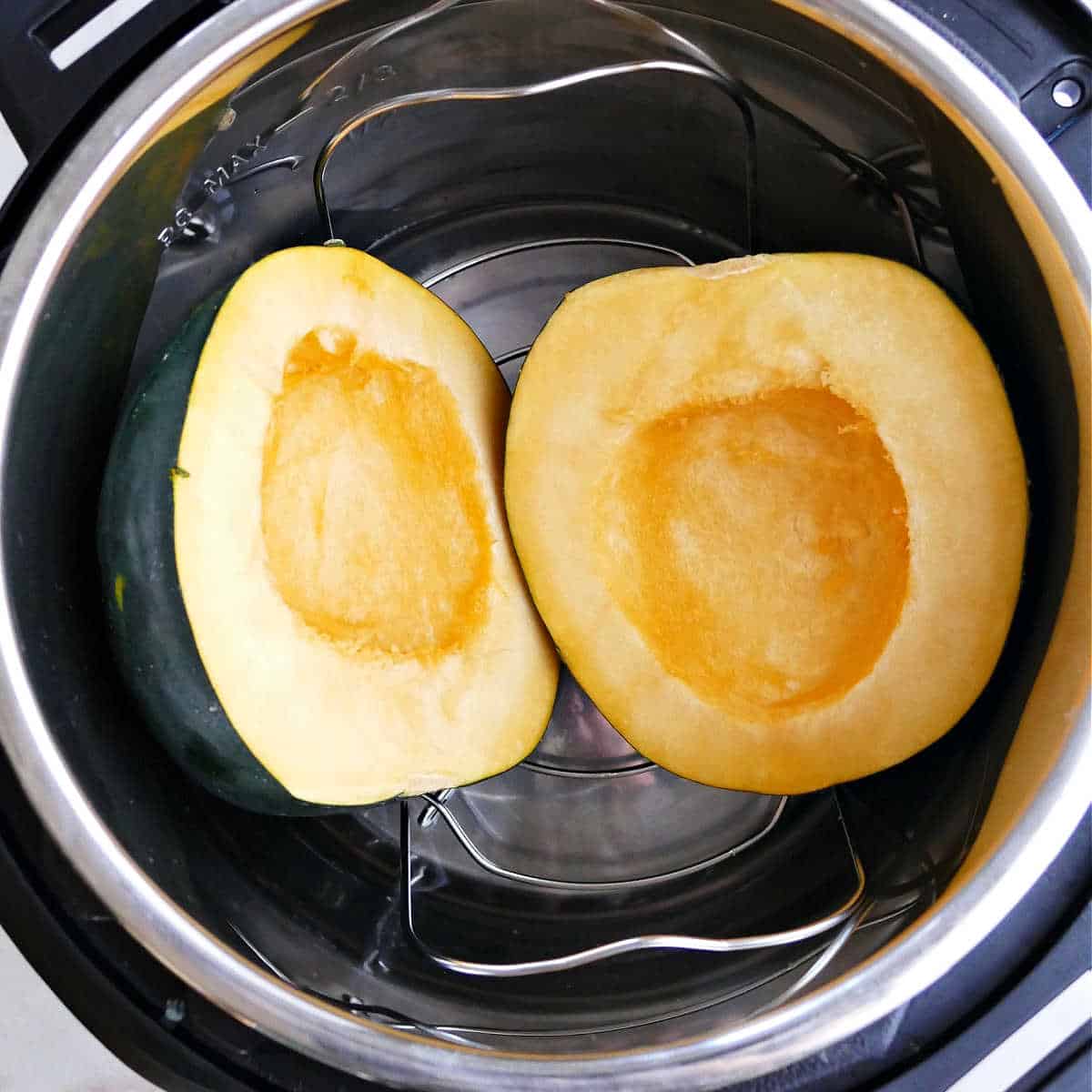 two acorn squash halves on a trivet in an instant pot