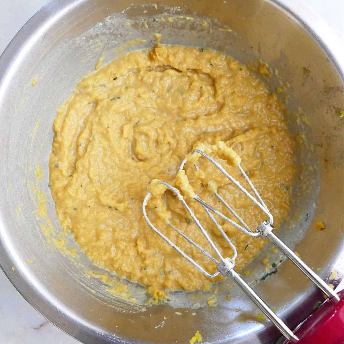 mashed acorn squash blended in a bowl with a hand mixer