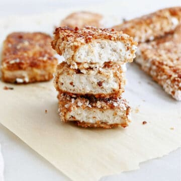 three pieces of crispy tofu stacked on top of each other on parchment