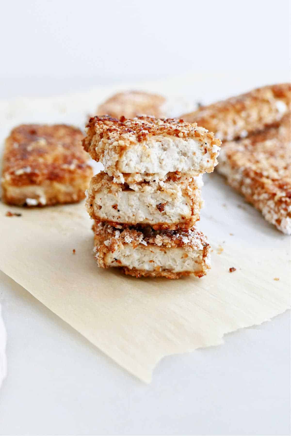 three pieces of crispy tofu stacked on top of each other on parchment
