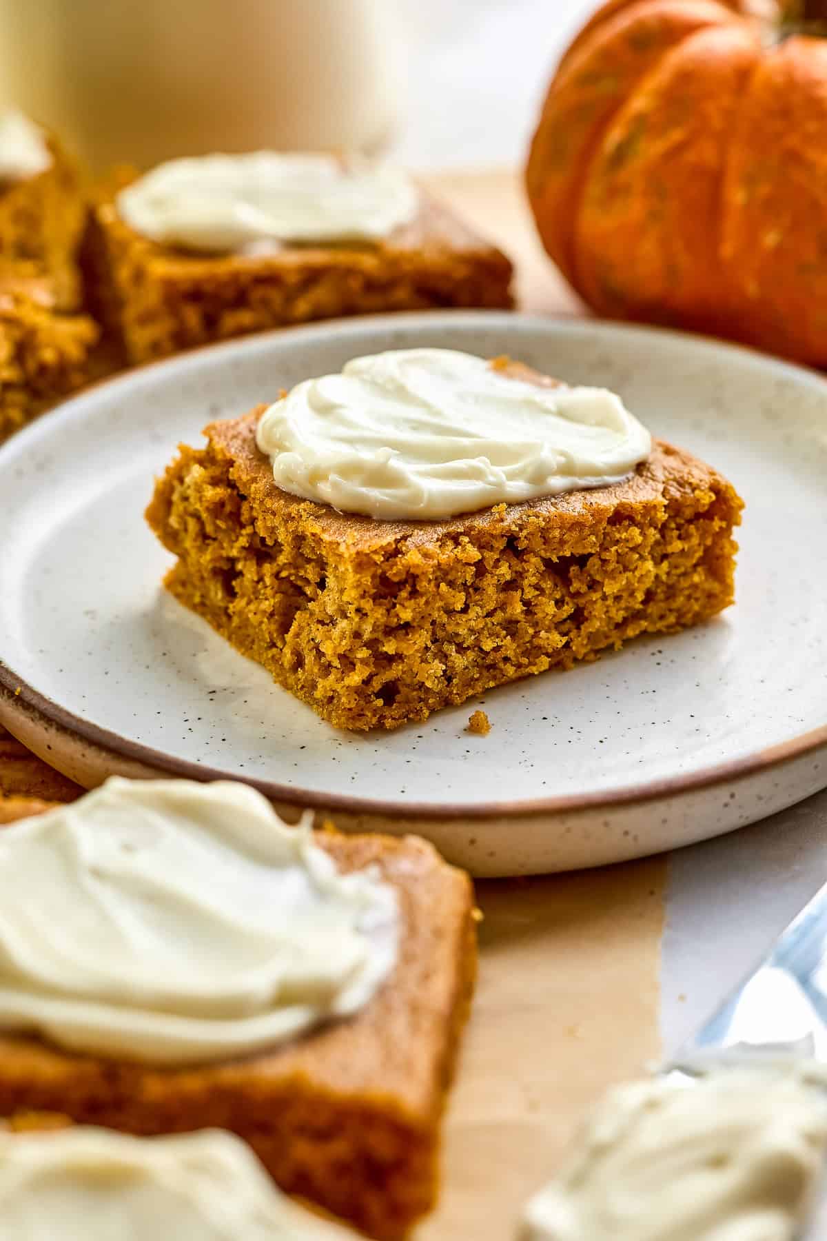 Moist pumpkin bar on a plate with cream cheese frosting.