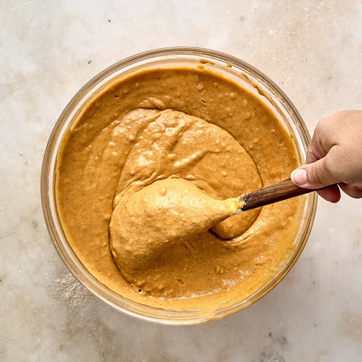 Woman using a rubber spatula to combine wet and dry ingredients for pumpkin bars.