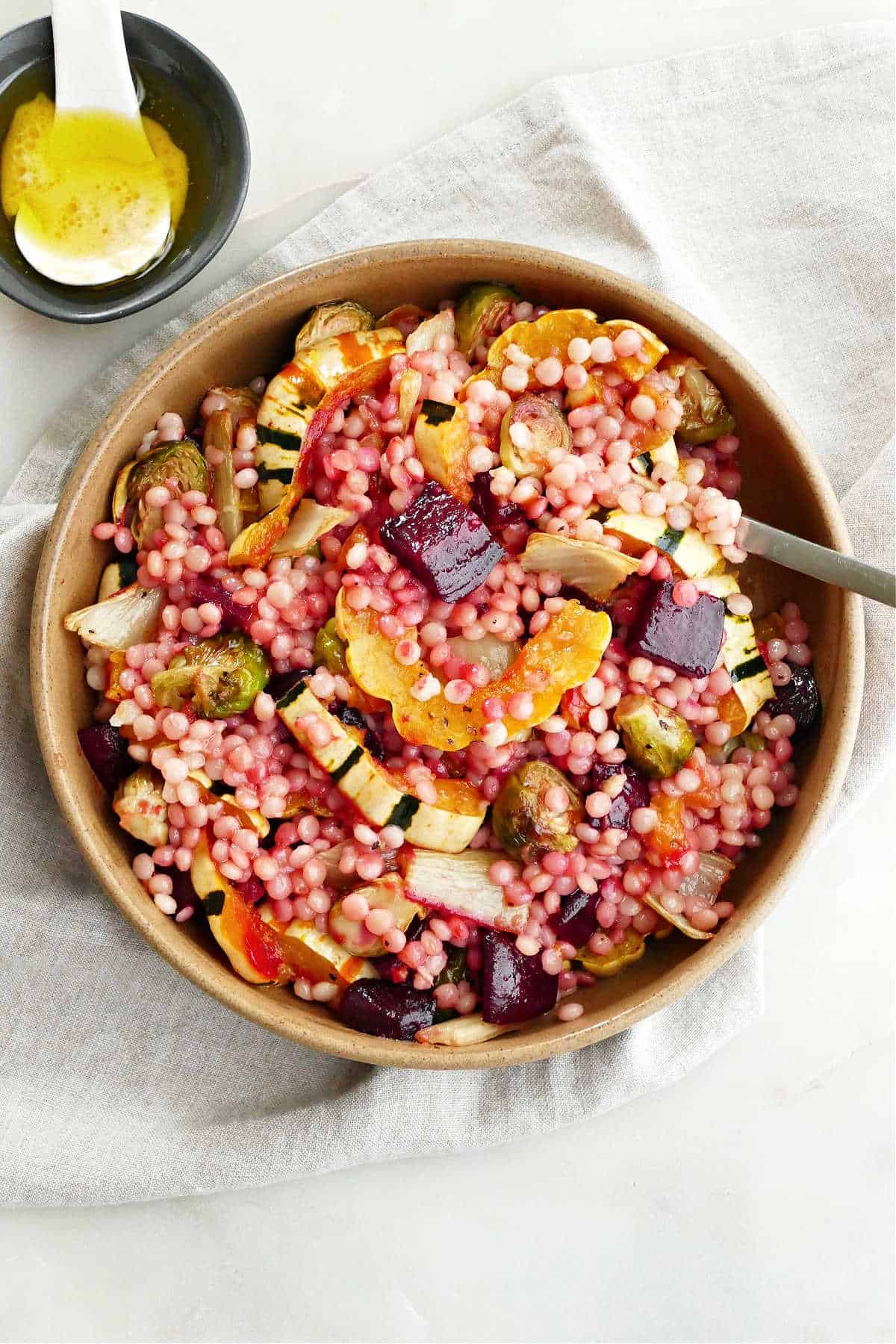 fall vegetables and couscous in a serving bowl with a spoon