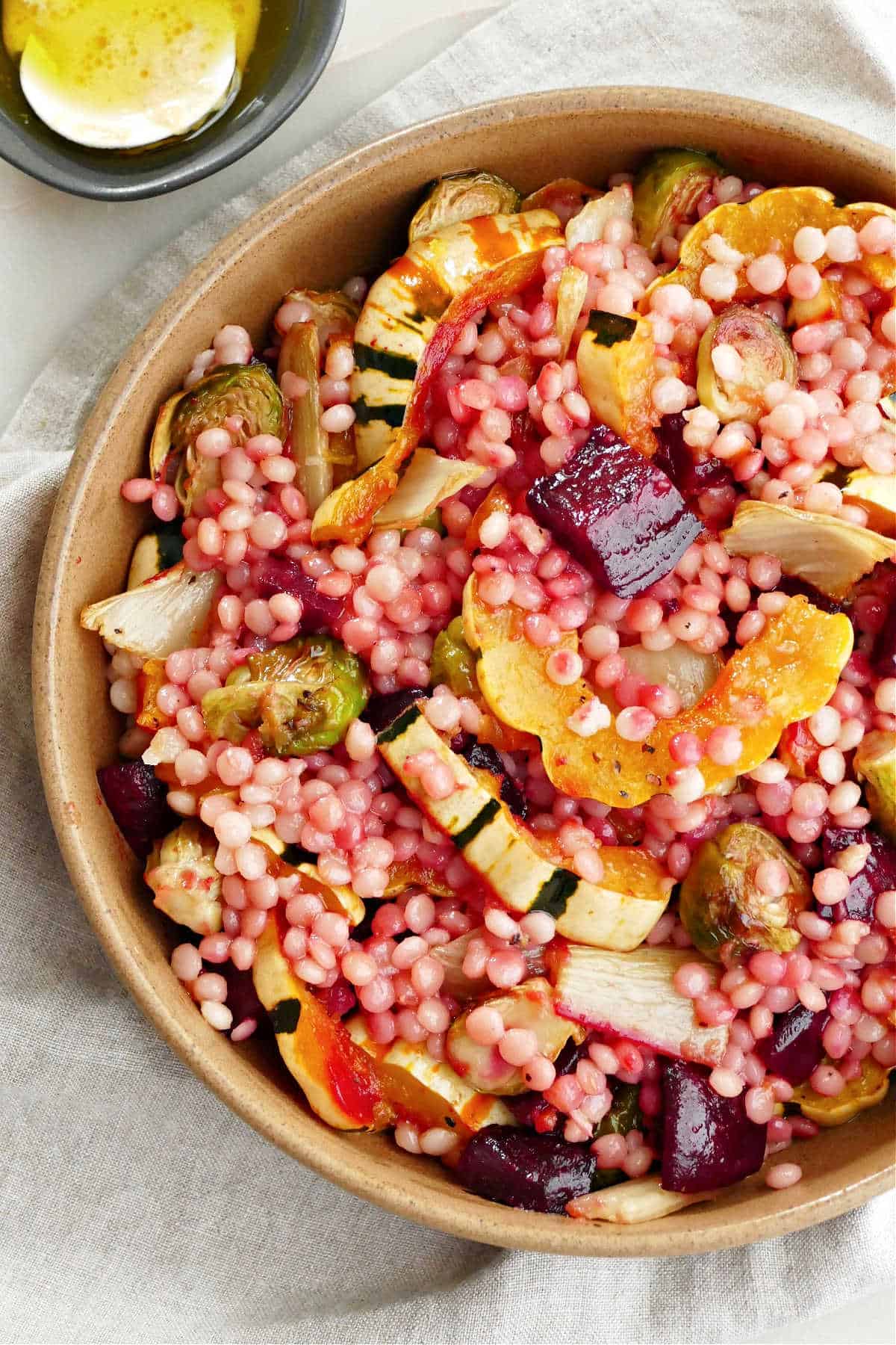 roasted fall vegetable and couscous salad with apple cider dressing in a serving bowl