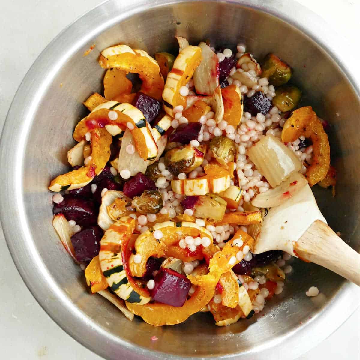 roasted fall vegetables and couscous stirred together in a mixing bowl