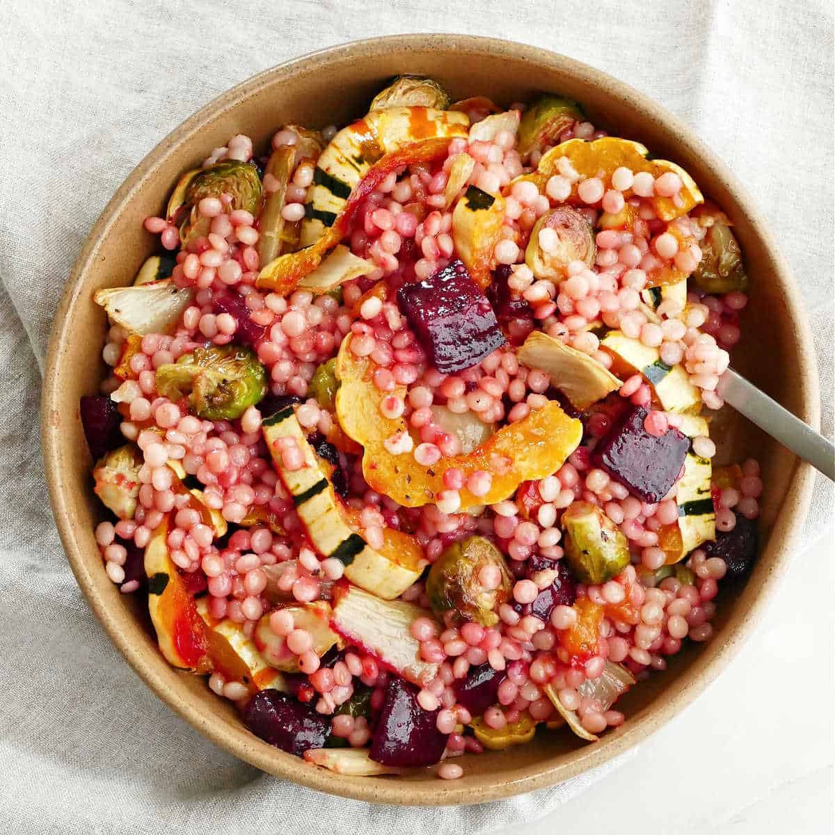 fall vegetables and couscous in a serving bowl with a spoon