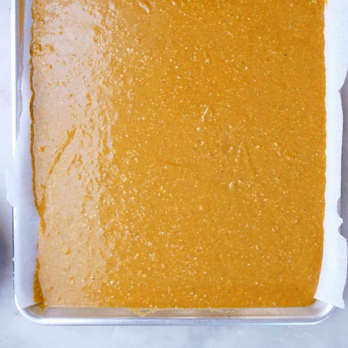 pumpkin bar batter spread on a half sheet pan before baking