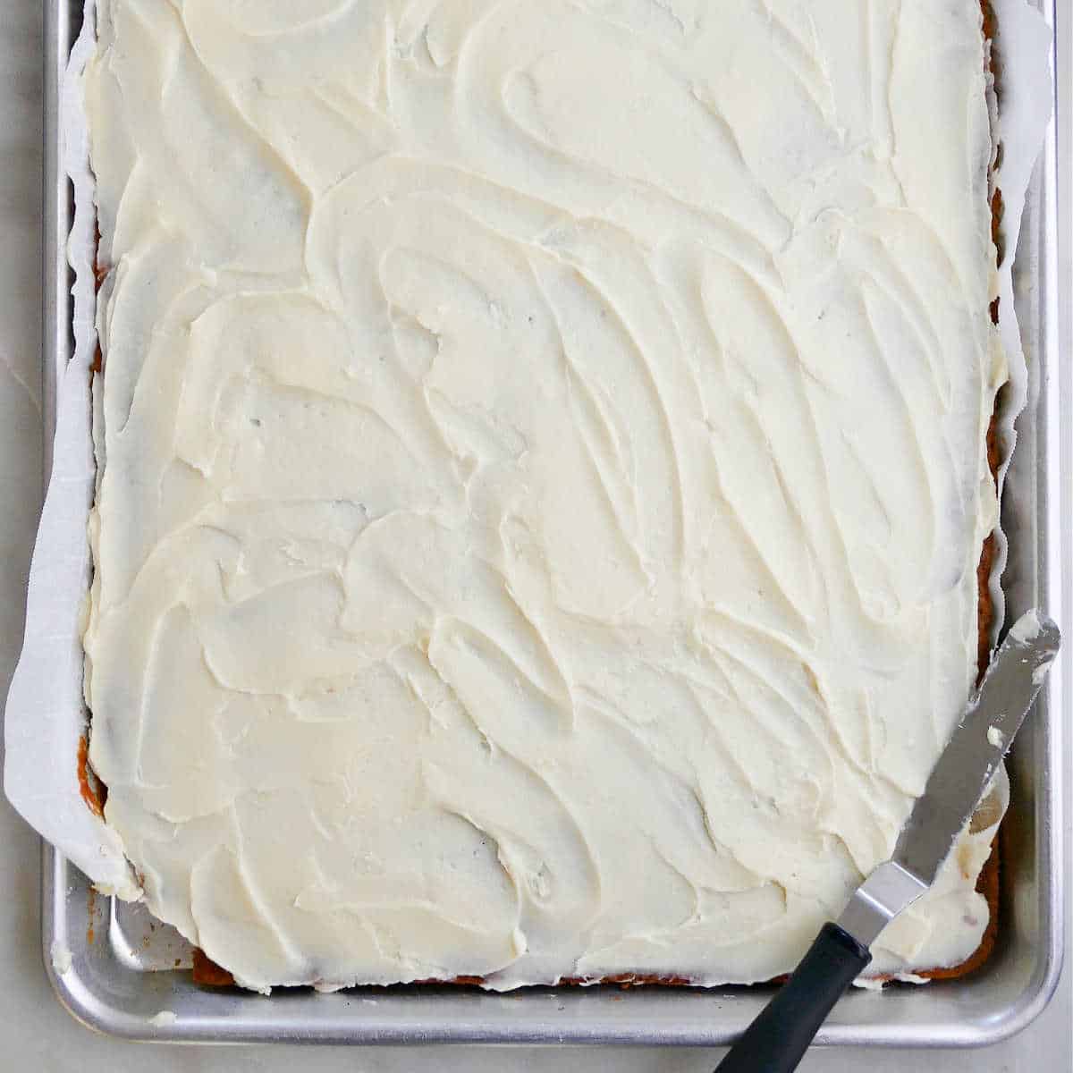 pumpkin bars on a sheet pan spread with cream cheese frosting