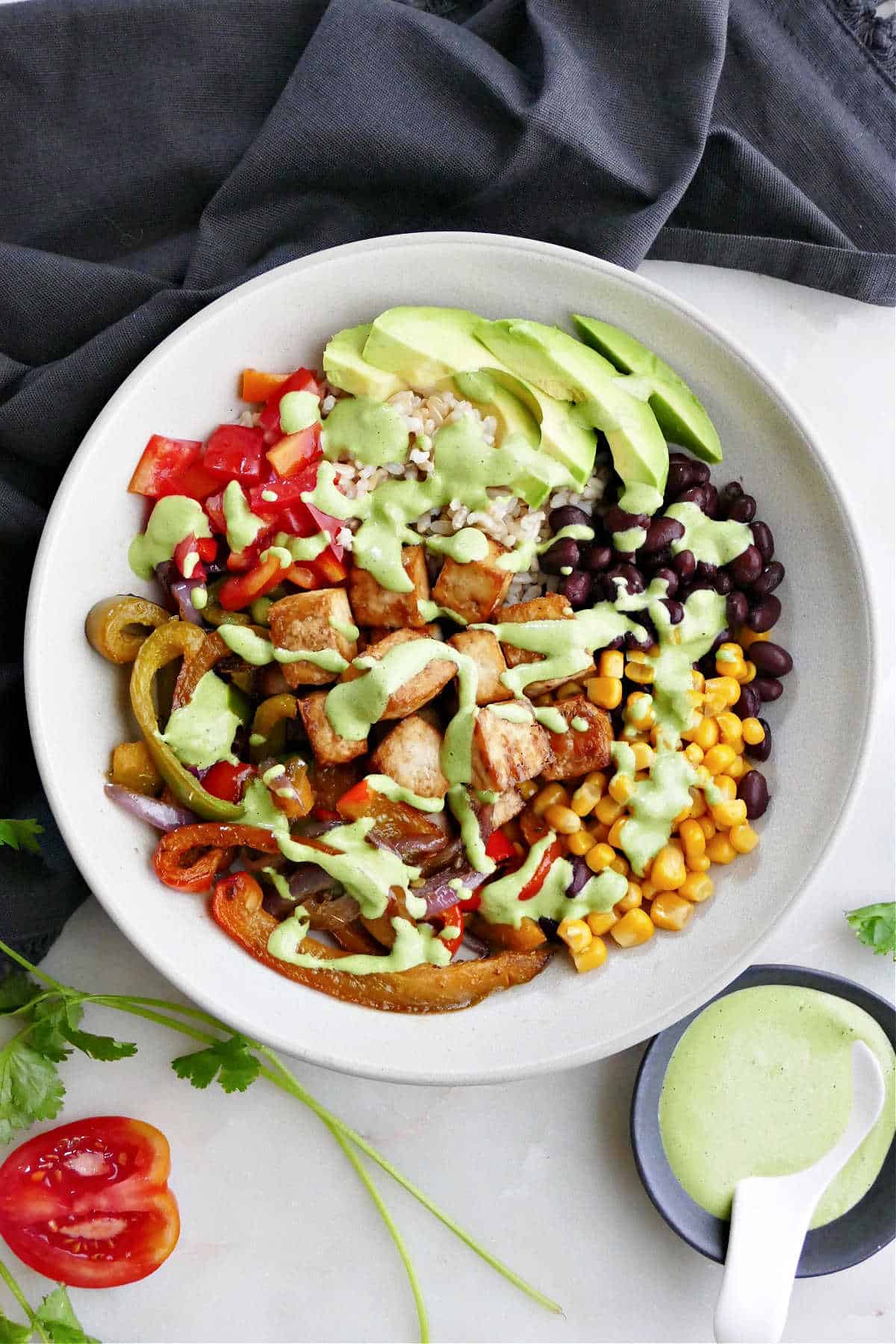 tofu burrito bowl with tahini dressing on a counter next to a napkin