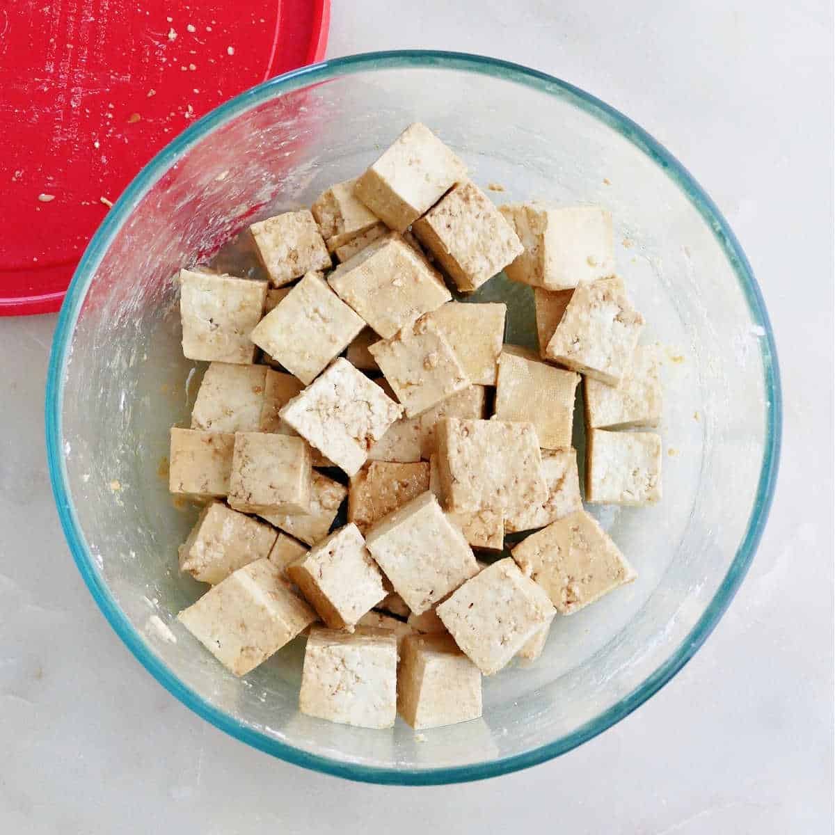 tofu cubes in a glass bowl drizzled with soy sauce and cornstarch