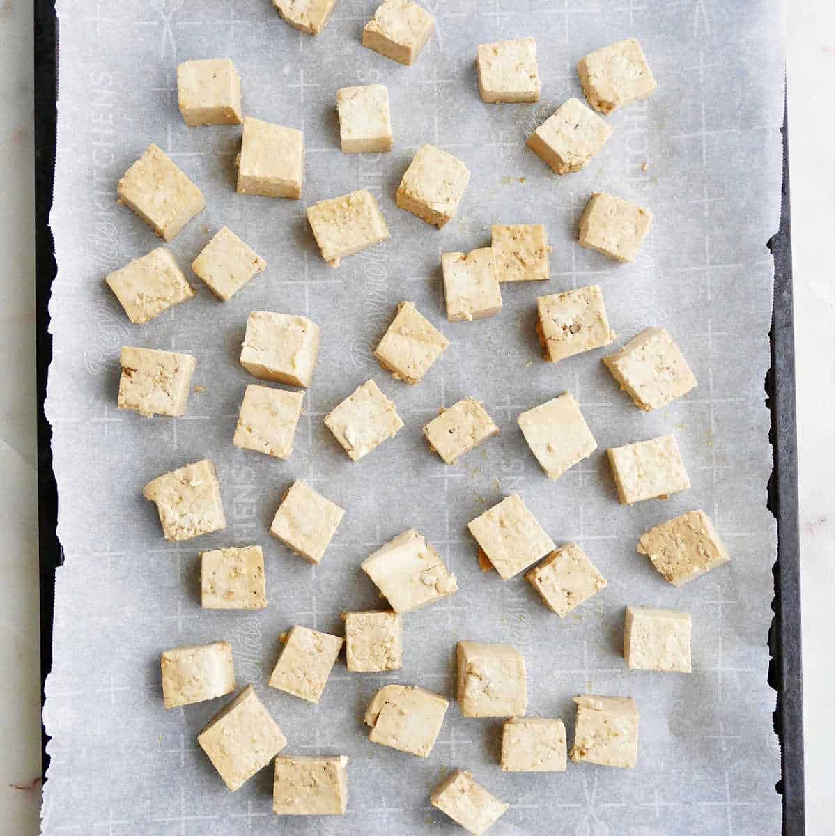 marinated tofu cubes on a baking sheet before going in the oven