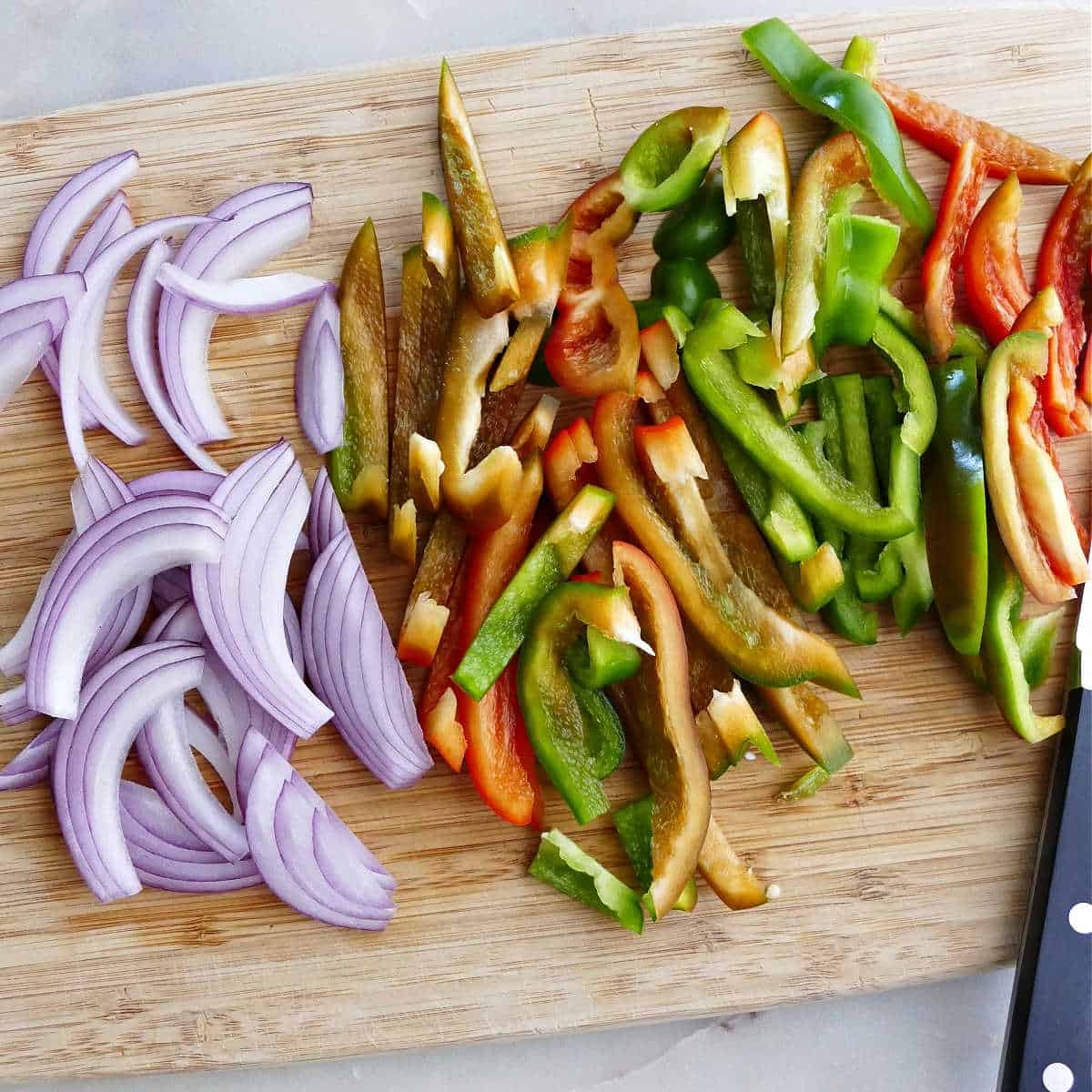 sliced red onion and bell peppers on a cutting board