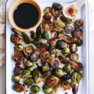 candied brussels sprouts on a rectangular platter with a bowl of glaze