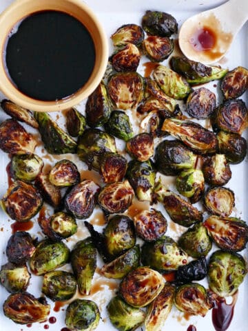 candied brussels sprouts on a rectangular platter with a bowl of glaze