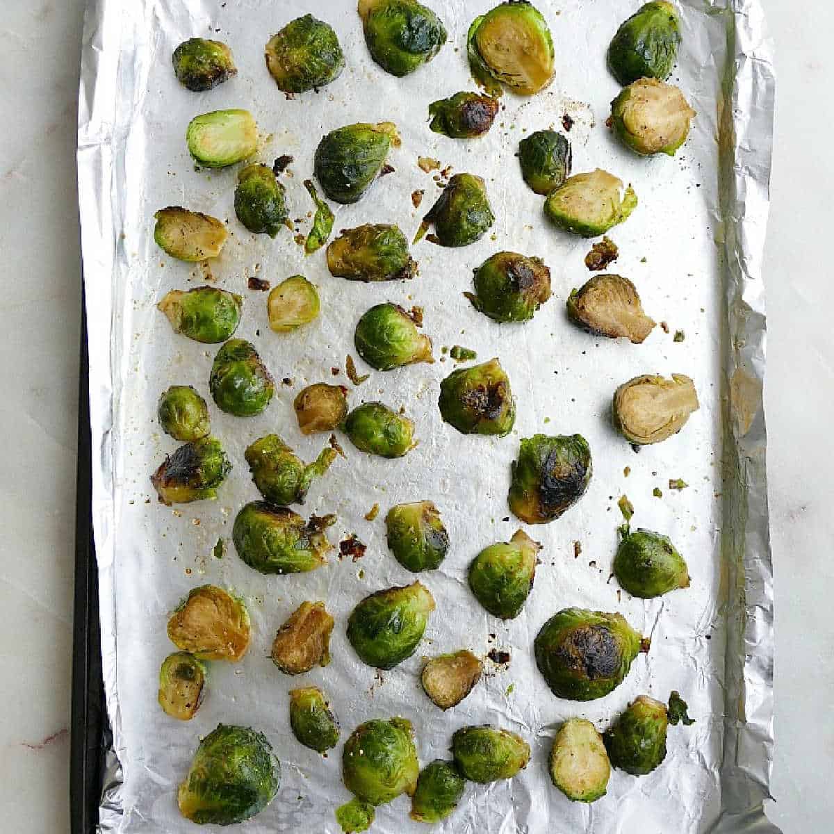 Brussels sprouts baked on a baking sheet lined with foil