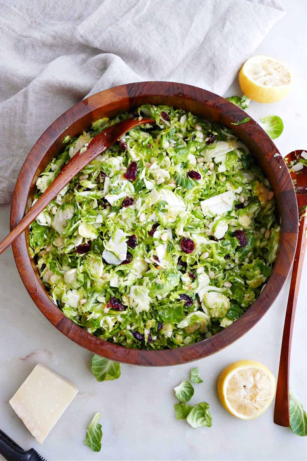 Brussels sprouts salad in a wooden salad bowl with tongs on a counter