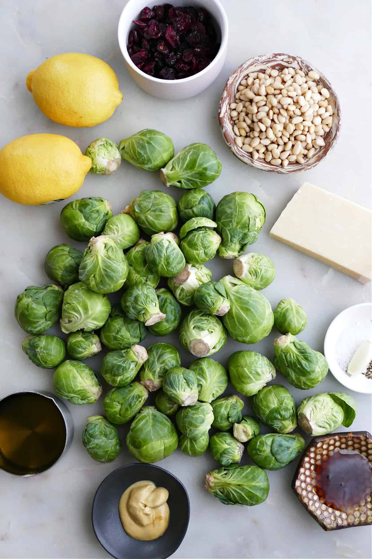 Brussels sprouts, lemons, pine nuts, parmesan, and dressing ingredients on a counter