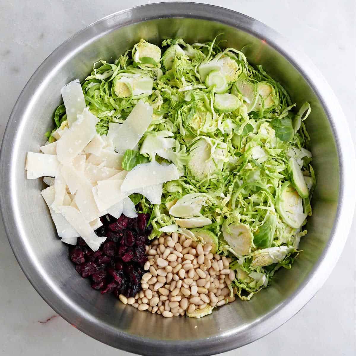 ingredients for Brussels sprouts salad in a large mixing bowl on a counter