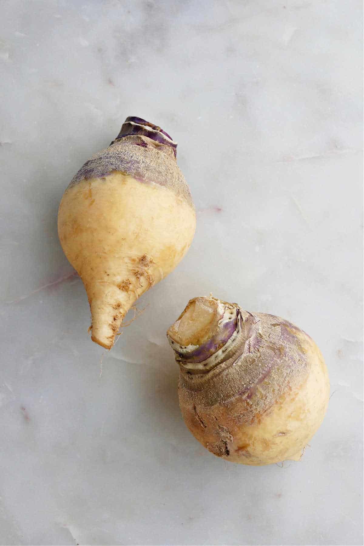 two rutabaga next to each other on a marble counter