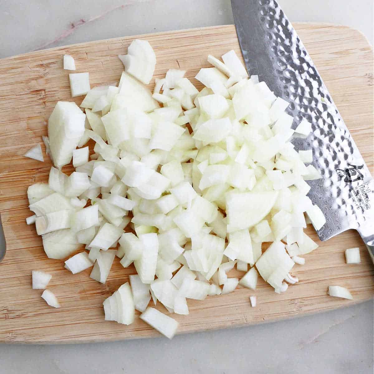 diced yellow onion on a cutting board with a chef's knife