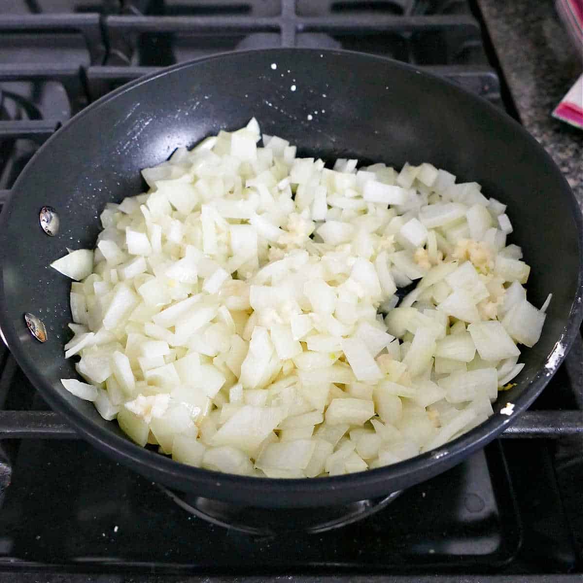diced onion cooking with olive oil and garlic in a skillet