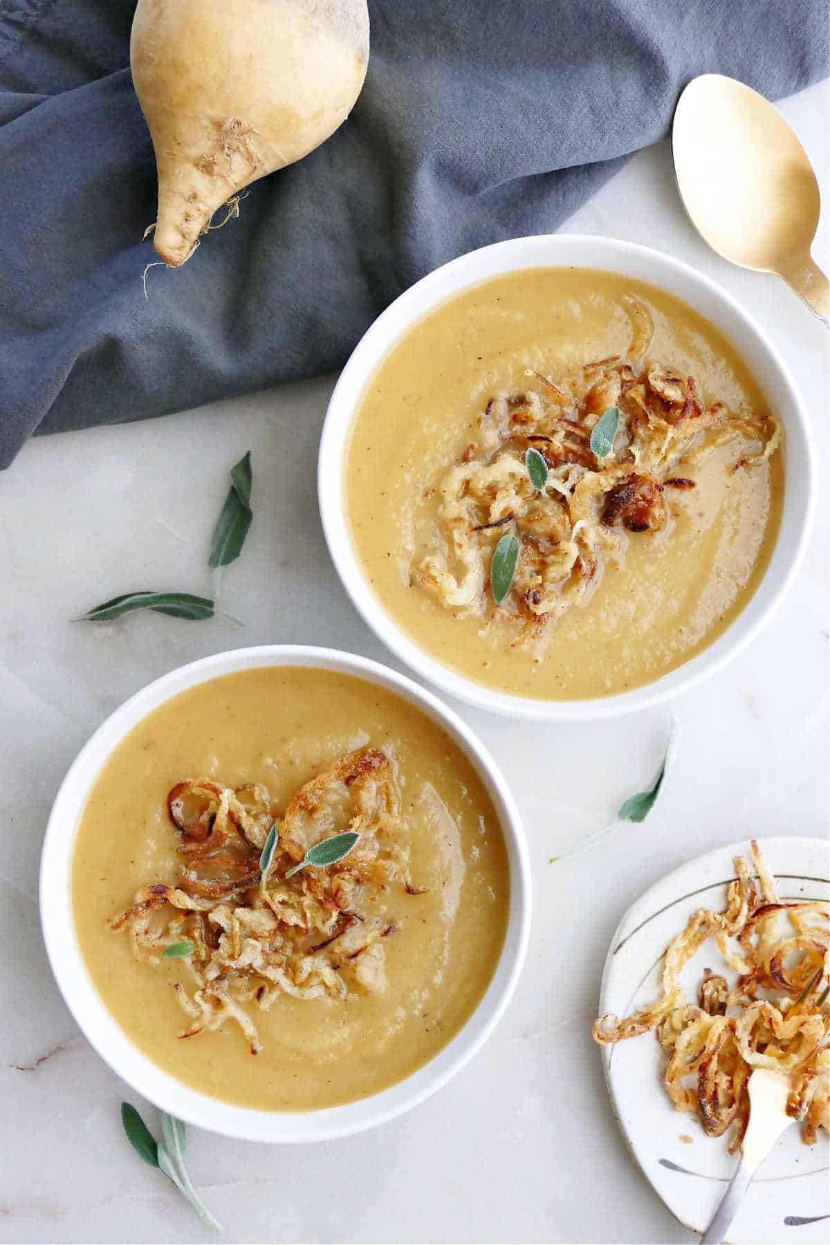 two bowls of swede soup with crispy onions next to each other on a counter