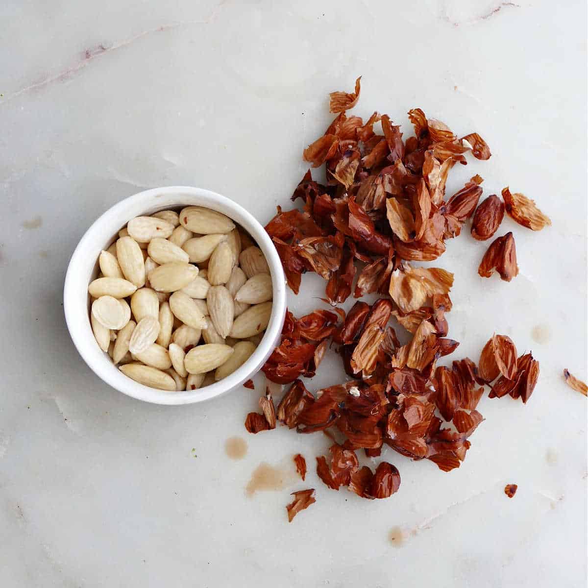 blanched almonds in a bowl with their skins removed and placed next to bowl