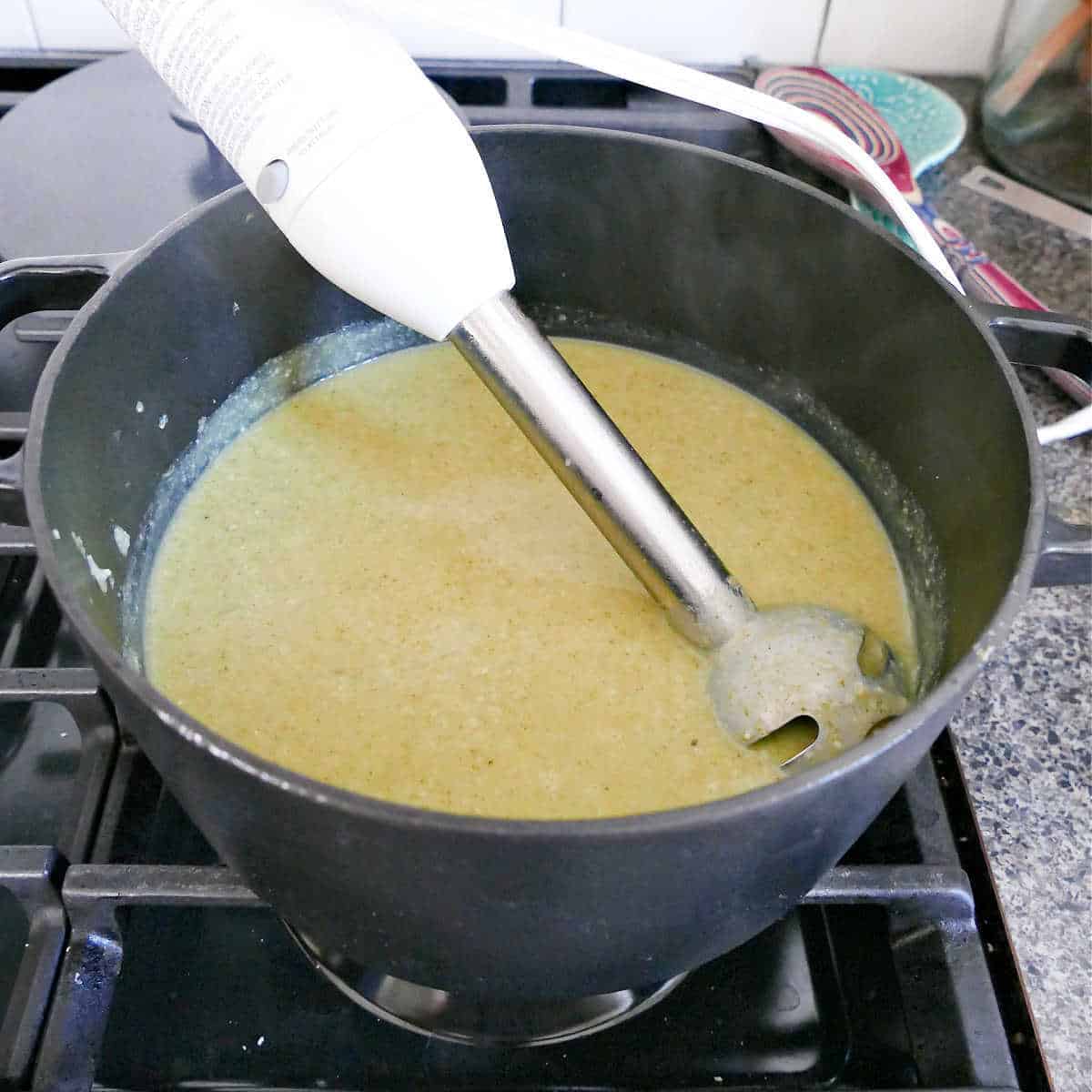 broccoli almond soup blended with a handheld blender in a soup pot