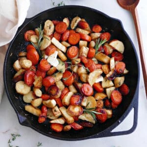 roasted carrots and parsnips with honey and herbs in a cast iron pan on a counter