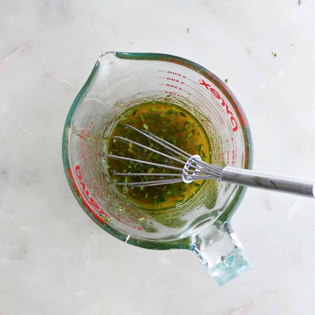 olive oil honey glaze being whisked in a measuring cup