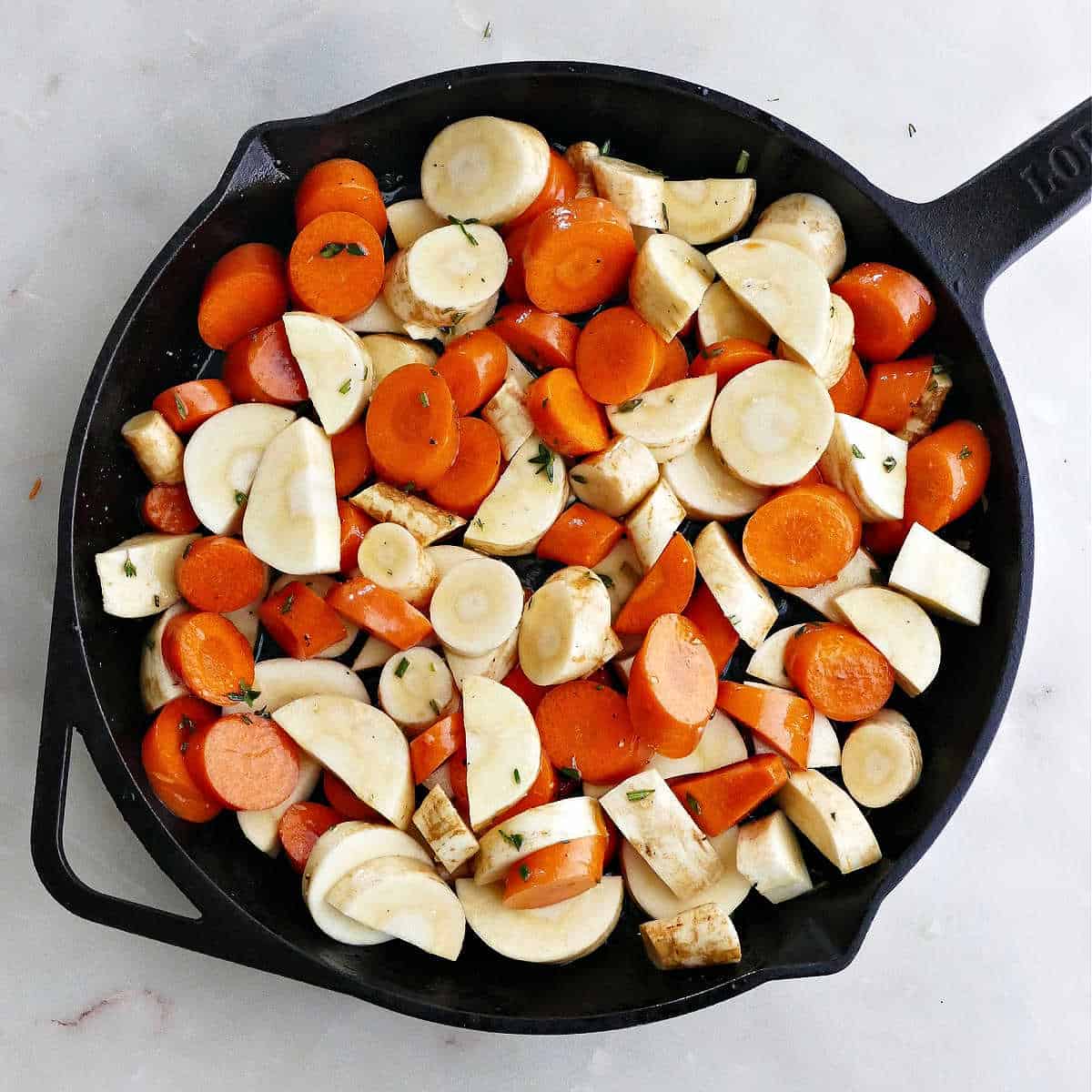 sliced carrots and parsnips in a cast iron pan before going into the oven to roast