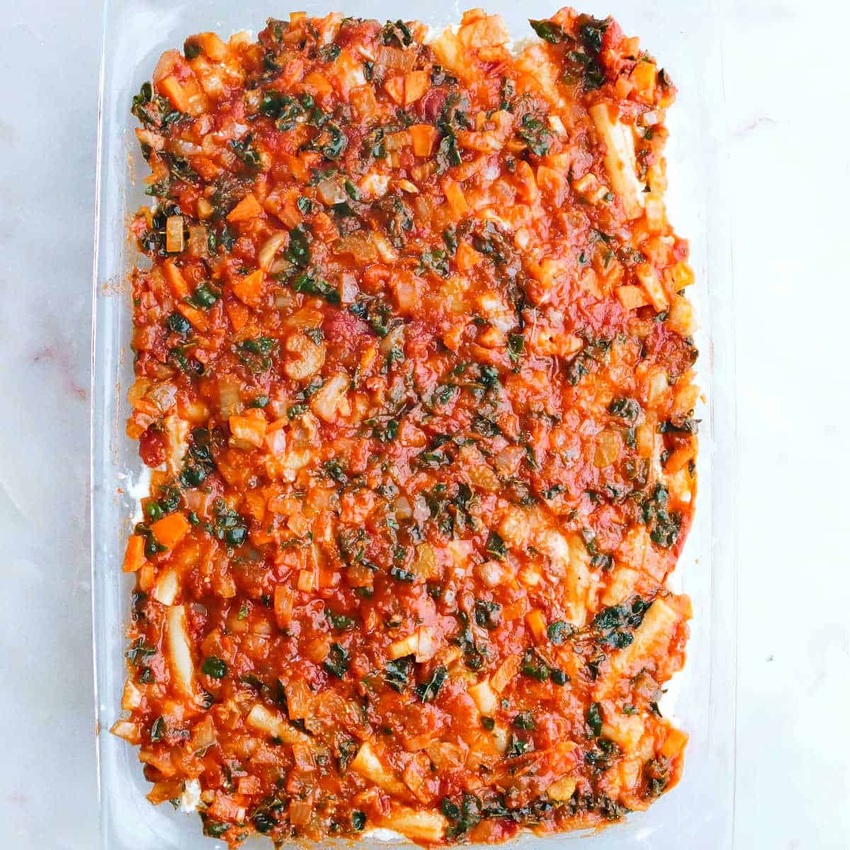 vegetable tomato sauce covering the ziti and cheese mixture in a dish