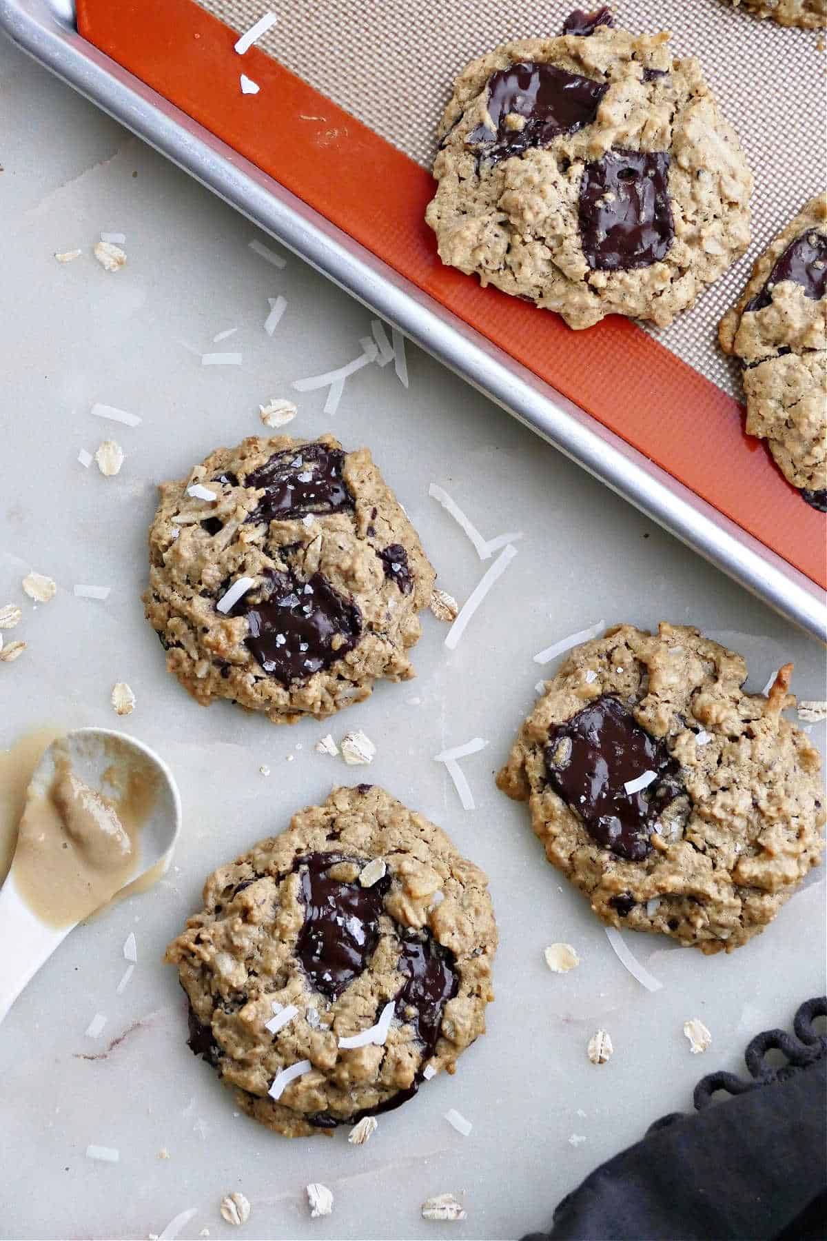 tahini cookies next to a baking sheet with rest of cookies on a counter