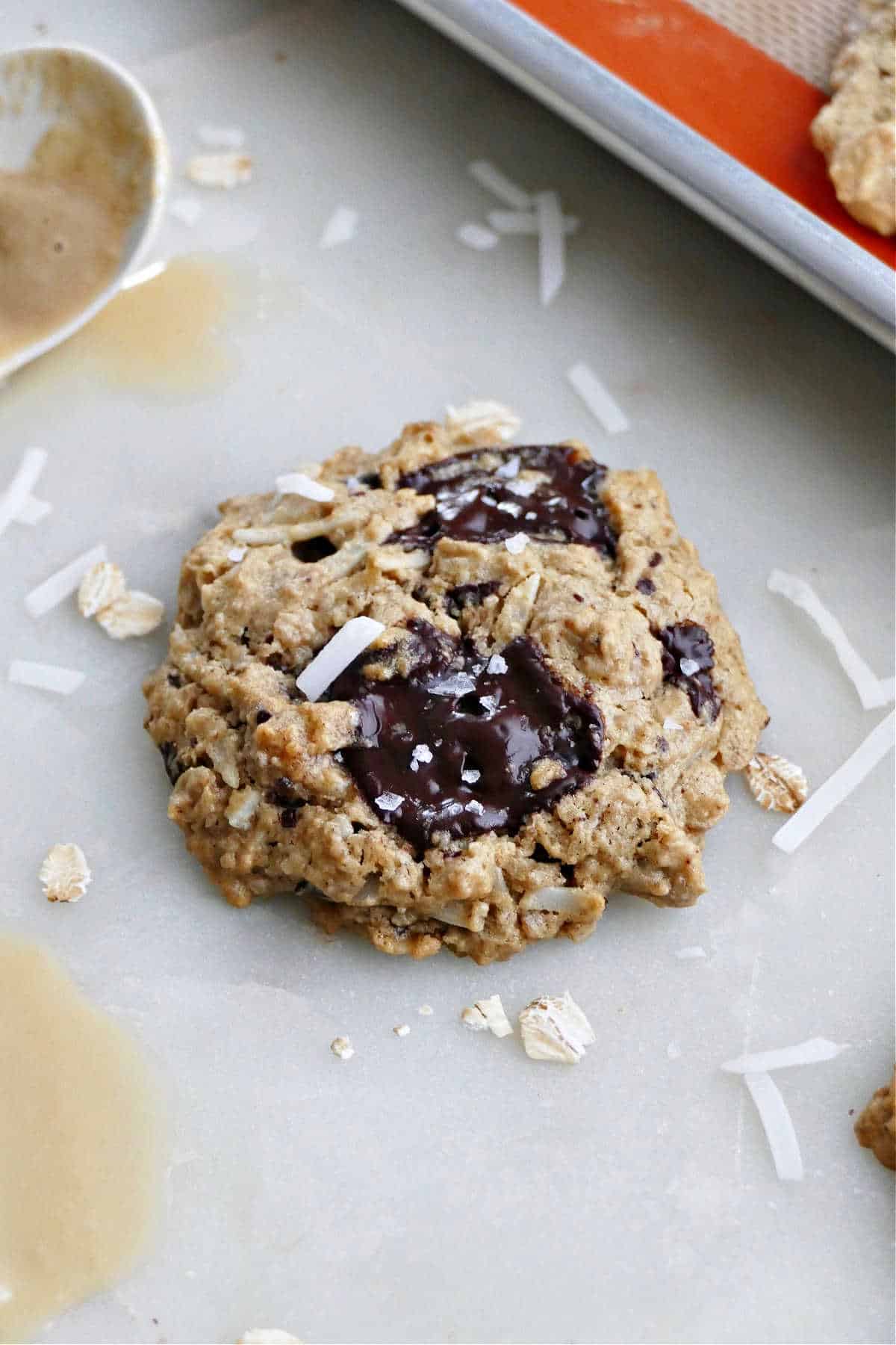 oatmeal tahini cookie next to a spoon of tahini on a counter