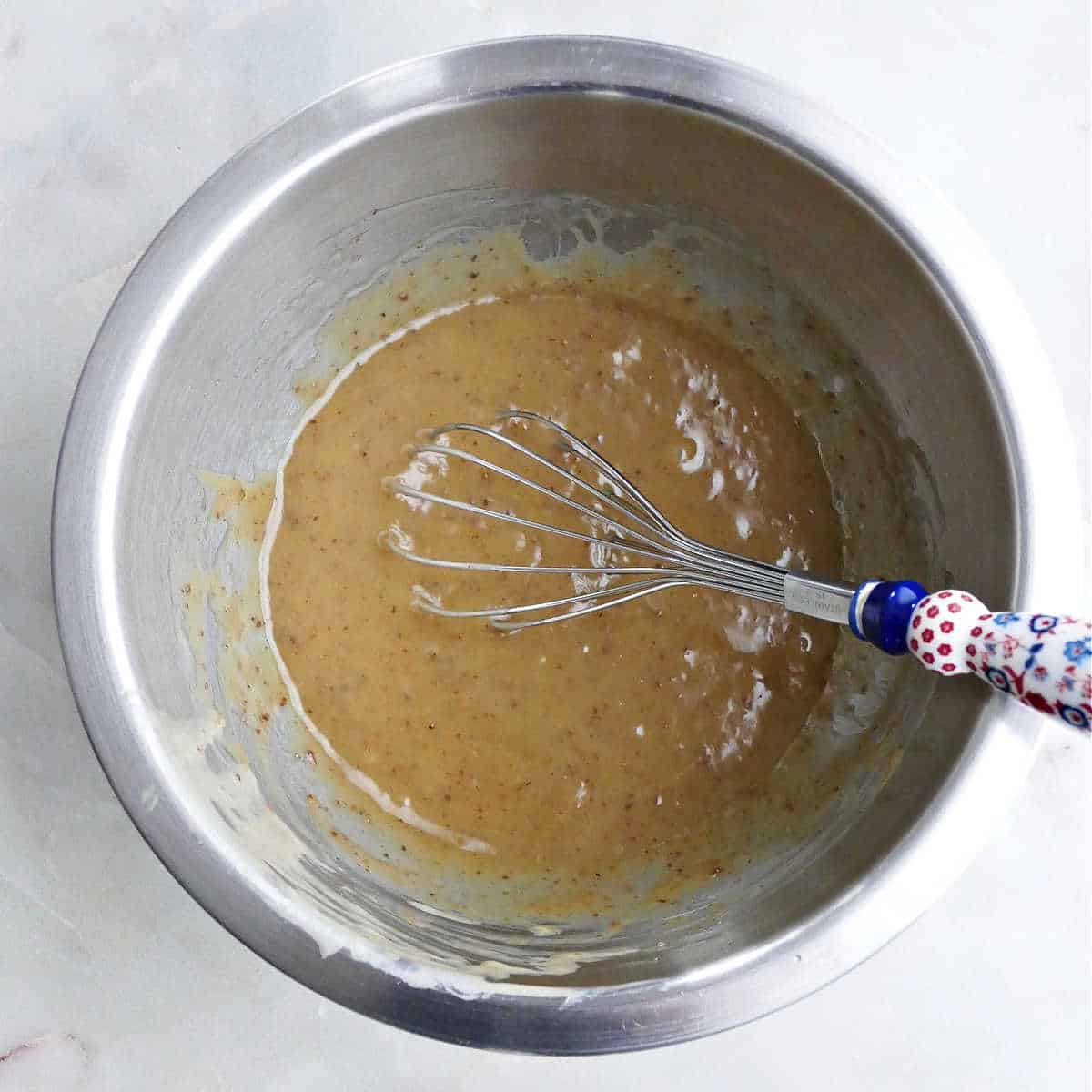 wet ingredients for tahini cookies in a bowl with a whisk