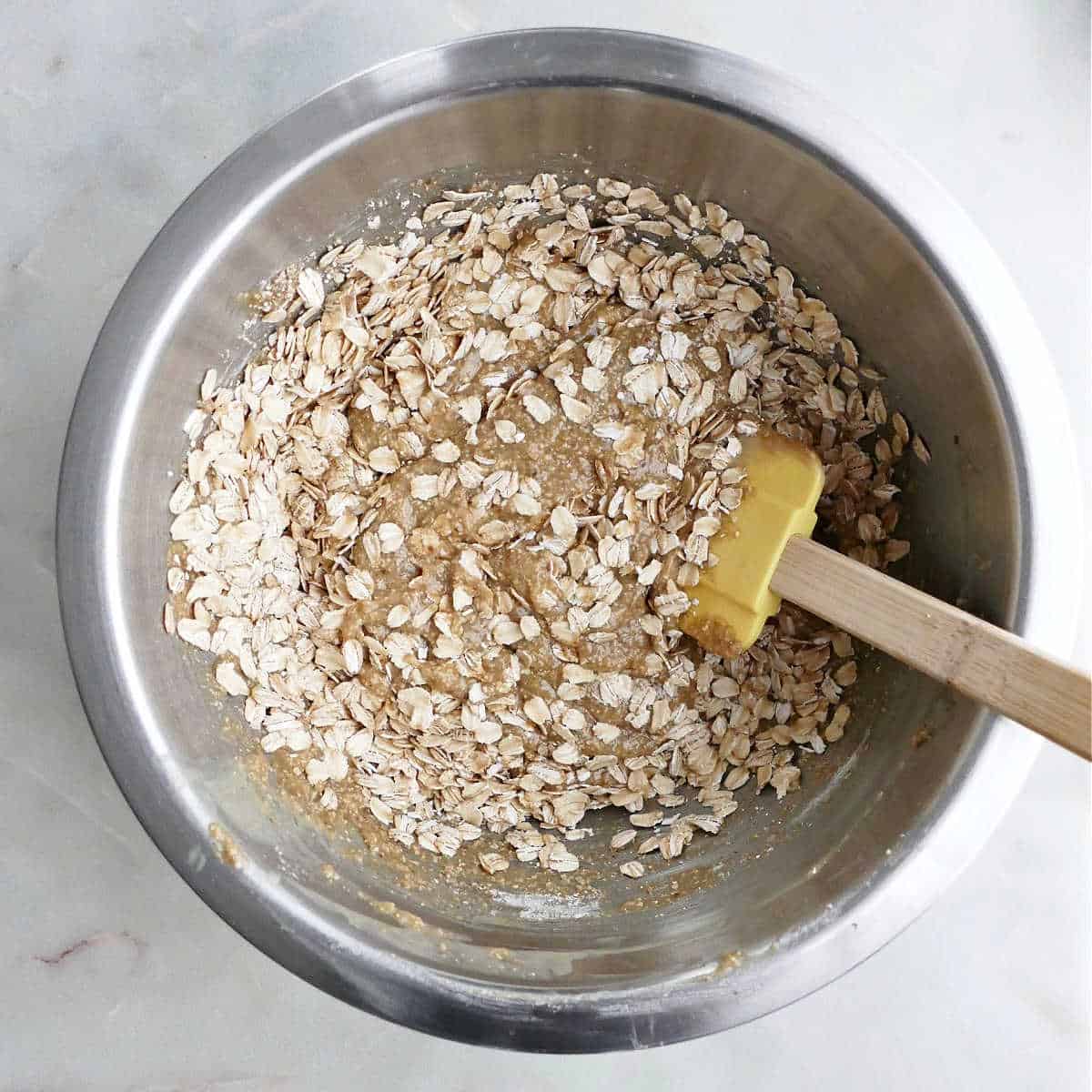 oats being added to a bowl wet ingredients for tahini cookies