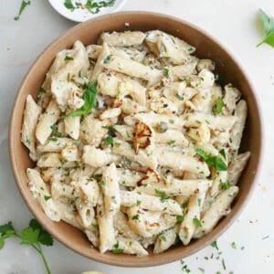 tahini pasta with cauliflower in a bowl next to herbs and lemon