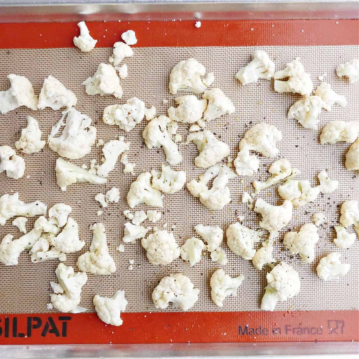 cauliflower florets on a lined baking sheet before roasting