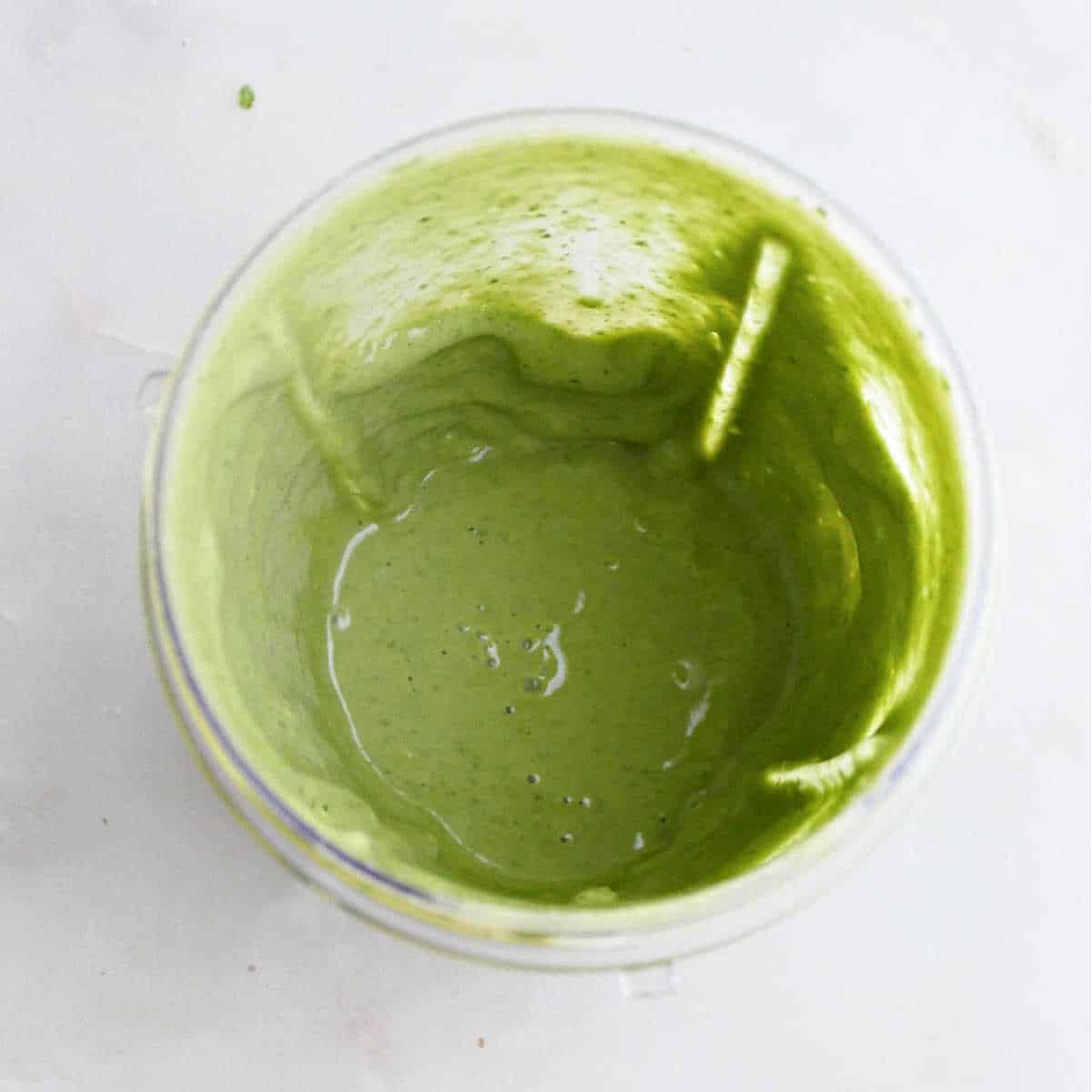 basil tahini sauce blended in a cup on a counter