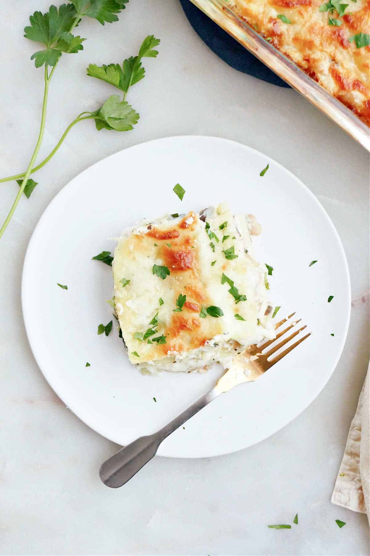 slice of vegetable lasagna on a plate with a fork