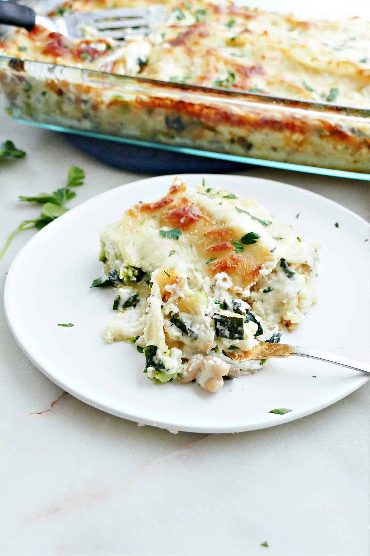 slice of vegetable lasagna on a plate with a fork cut into it