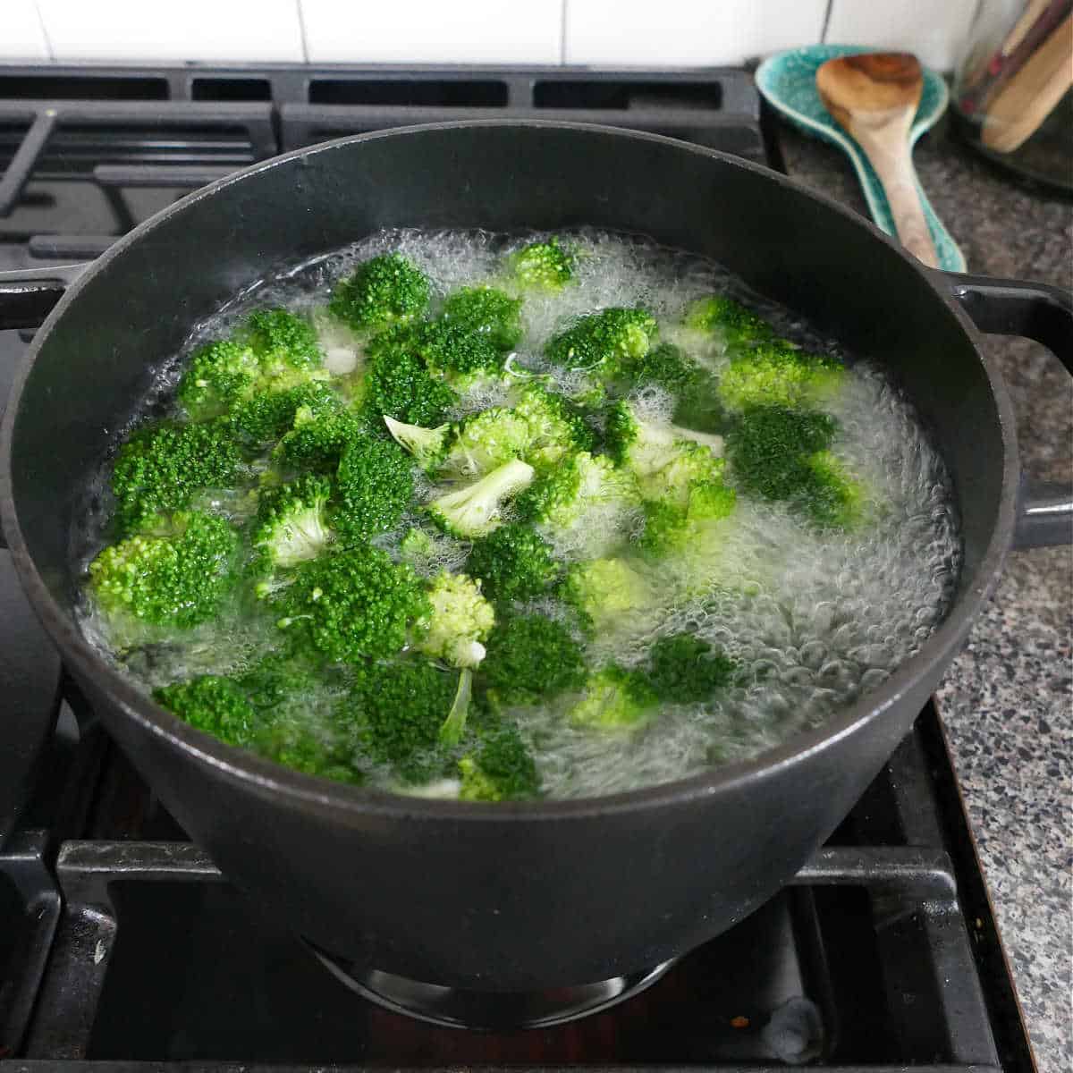 broccoli florets boiling in a pot of water on a stove