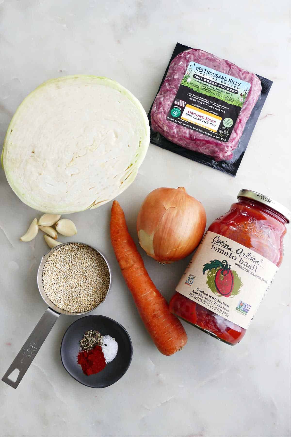 cabbage, ground beef, onion, carrot, tomato sauce, quinoa, and spices on a counter