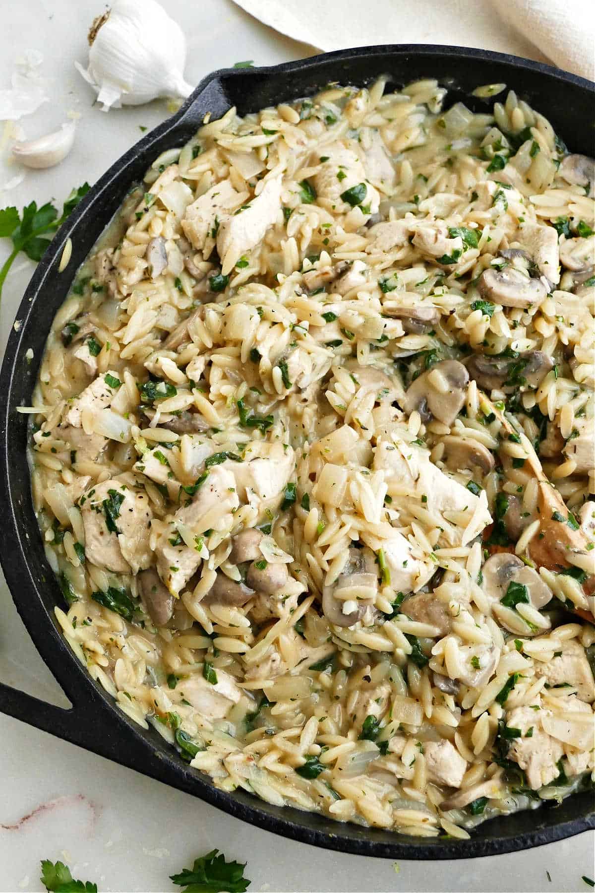 chicken mushroom orzo skillet dinner with a wooden spoon on a counter