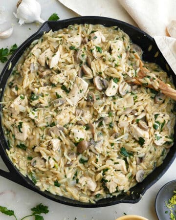 mushroom orzo and chicken dish in a cast iron skillet on a counter