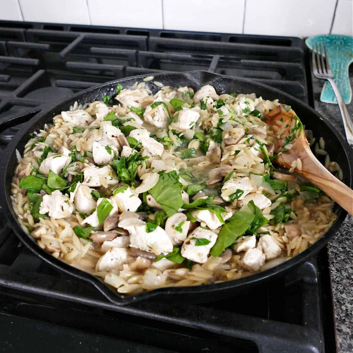 chicken mushroom orzo dinner cooking in a cast iron skillet on a stove