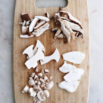 five different types of mushrooms cut up on a cutting board