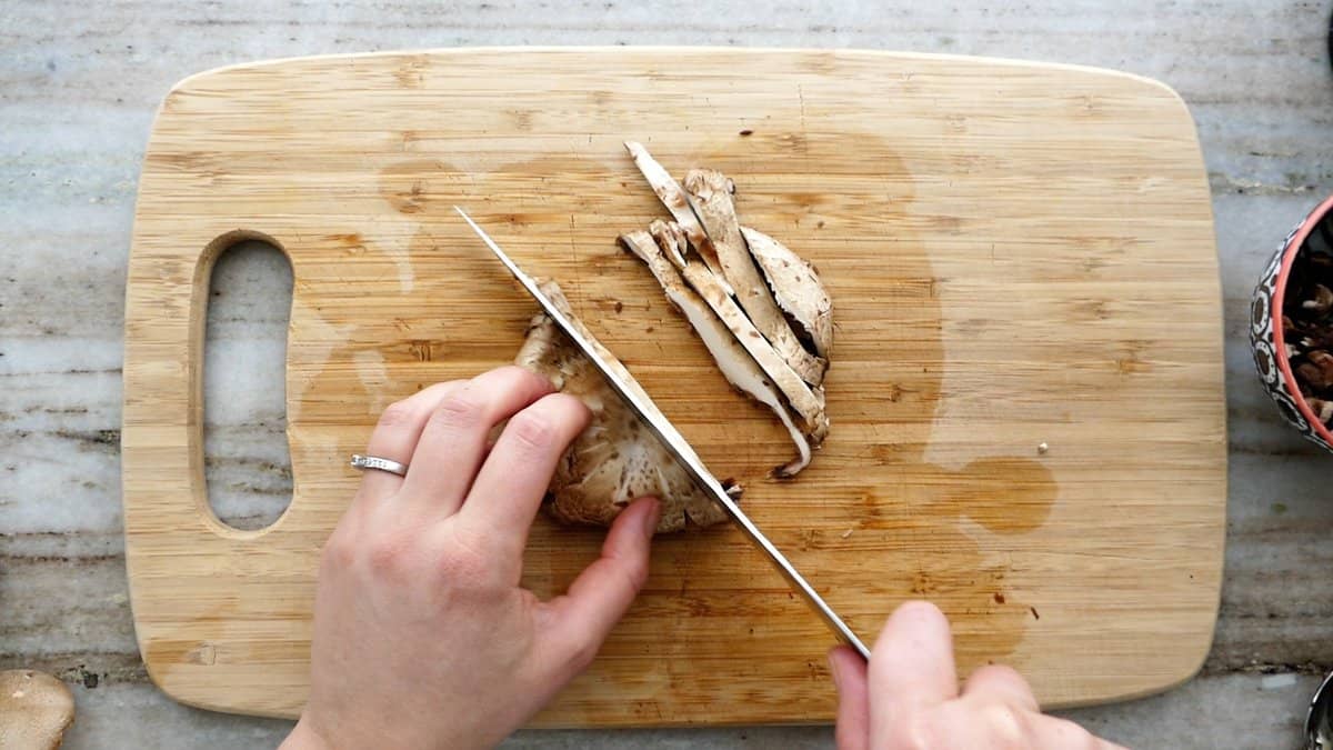 woman slicing a portobello mushroom on a cutting board