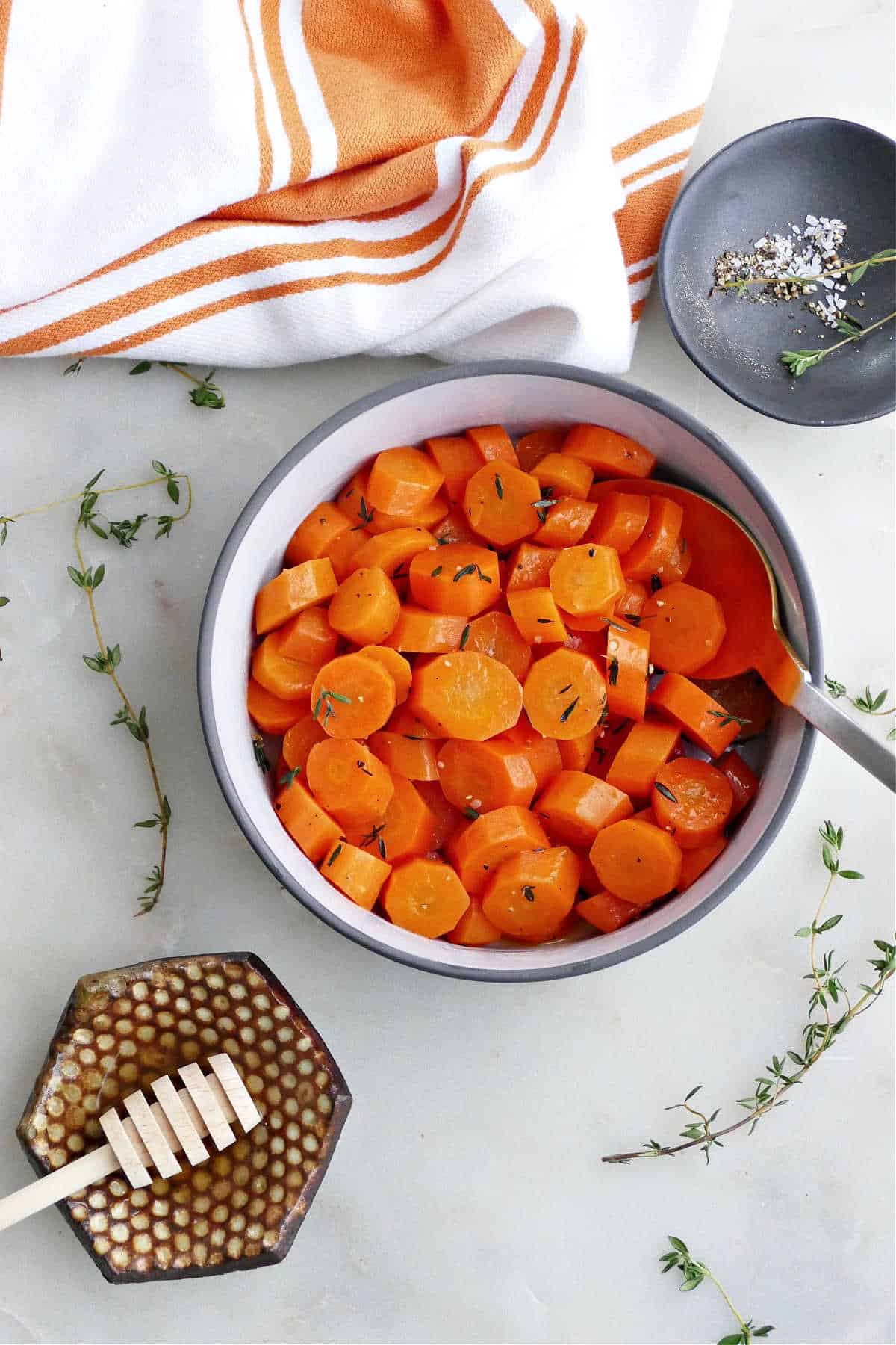 microwave carrots in a serving bowl surrounded by toppings